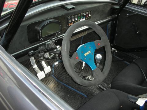1998 Ford Crown Victoria - The interior of a modified vehicle features a racing steering wheel, digital display, and safety roll cage.