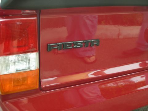 1998 Ford Crown Victoria - Close-up of a red car's rear, showing the FIESTA badge and a Ford taillight.