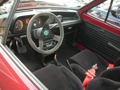 1998 Ford Crown Victoria - The interior of a classic car features racing seats, a custom steering wheel, and a manual transmission shifter.