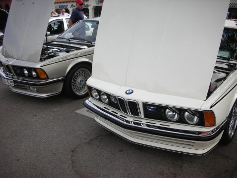 1998 Ford Crown Victoria - Two BMW E24 6 Series cars are parked side-by-side with their hoods open.