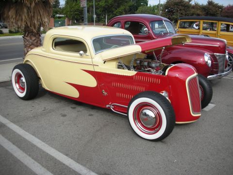 1998 Ford Crown Victoria - Custom hot rod coupe with flame graphics and exposed engine sits in a parking lot with other classic cars.