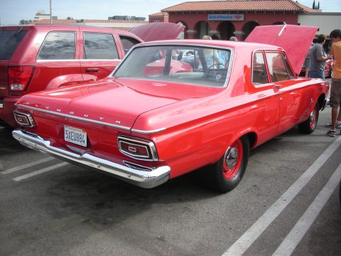 1998 Ford Crown Victoria - A bright red 1964 Plymouth sedan is parked next to a red SUV, with its hood open.