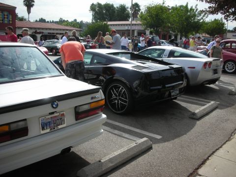 1998 Ford Crown Victoria - Several sports cars are gathered in a parking lot, with onlookers present.
