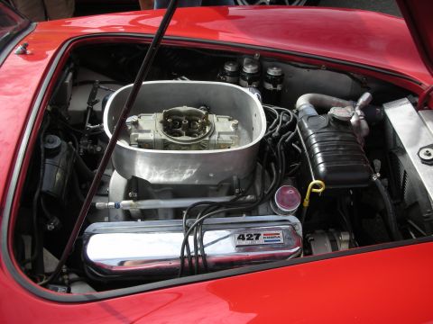 1998 Ford Crown Victoria - The engine bay of a red car features a prominent carburetor and a valve cover labeled '427 COBRA'.