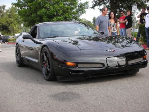1998 Ford Crown Victoria - Black Chevrolet Corvette C5 parked outdoors with people in the background.