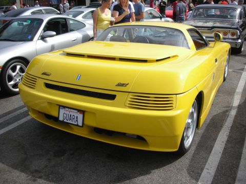 1998 Ford Crown Victoria - A yellow sports car is parked in a lot with other vehicles.