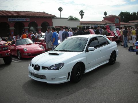 1998 Ford Crown Victoria - White Subaru Impreza WRX STI sedan parked at a car meet with other vehicles present.