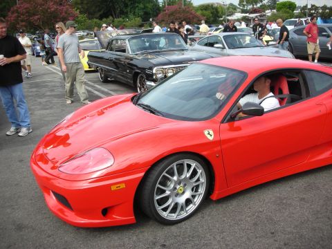 1998 Ford Crown Victoria - A red Ferrari 360 Modena is parked at a car meet, with other vehicles and people in the background.