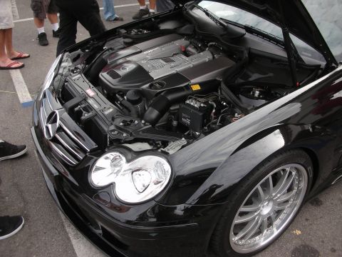1998 Ford Crown Victoria - The engine bay of a black Mercedes-Benz CLK-Class is displayed with the hood open, revealing its V8 engine.