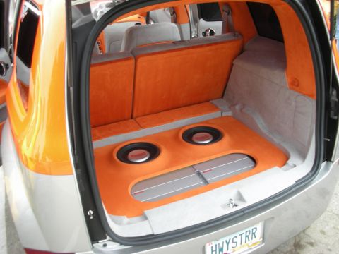 1998 Ford Crown Victoria - The rear of a car is customized with orange upholstery and audio equipment, including subwoofers and amplifiers.