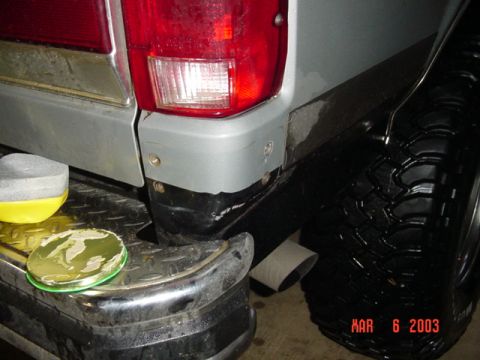 1989 Ford Bronco - A close-up shot of a vehicle's rear corner, showing the bumper, tire, and taillight assembly.