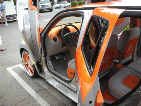1998 Ford Crown Victoria - The interior of a customized car with butterfly doors open, revealing orange accents and custom upholstery.