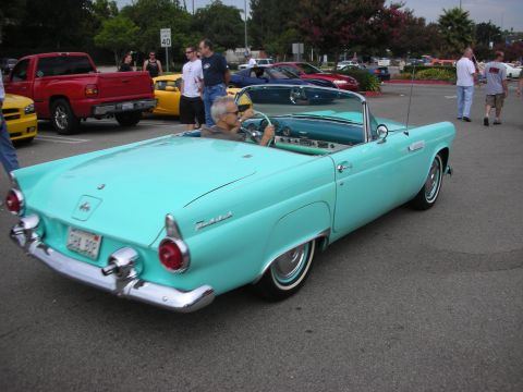 1998 Ford Crown Victoria - turquoise Ford Thunderbird convertible with a driver aboard sits in a parking lot car show, rear three-quarter view.