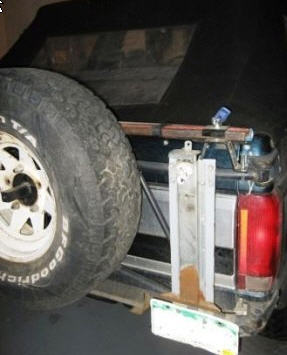 1995 Ford Bronco - The rear of a Ford Bronco shows a spare tire and a Hi-Lift jack mounted to the tailgate.