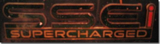 Close-up of an "SSEi SUPERCHARGED" badge with orange lettering and a red "i"