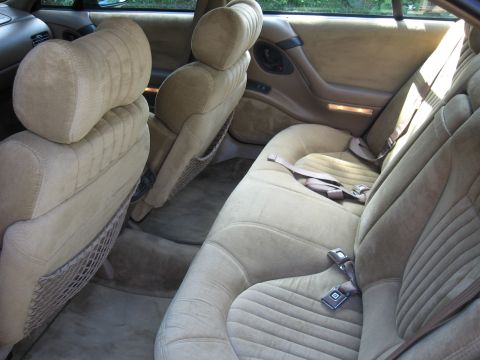 1992 Ford Crown Victoria - Interior view of a tan velour car interior with prominent seatbelts and door panel details.