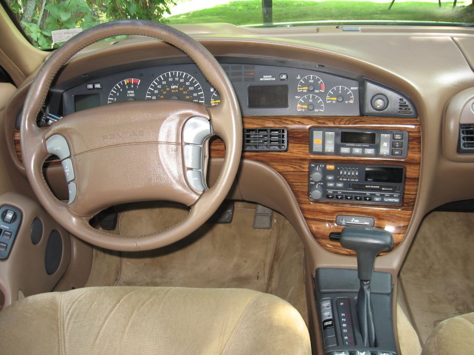 Interior view of a car dashboard with wood trim, showing the steering wheel, gauges, and radio