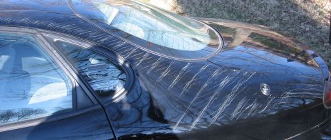 1999 Ford Taurus - This 1999 Ford Taurus shows significant damage to its rear body panels, with numerous long scratches marring the black paint.