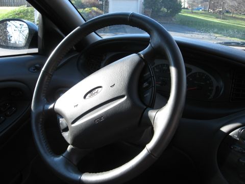 1999 Ford Taurus - Interior view of a 1999 Ford Taurus, focusing on the steering wheel and dashboard.