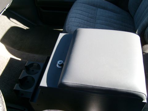 1989 Ford Bronco - Interior view of a vehicle's center console, a lockable compartment and dual cup holders.