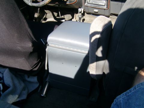 1989 Ford Bronco - The interior of a vehicle shows a gray center console unit positioned between the driver and passenger seats.