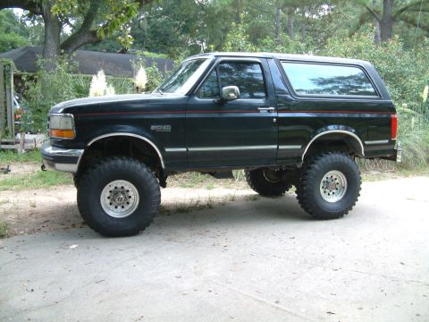 1992 Ford Bronco - This lifted 1992 Ford Bronco is presented in a dark green paint scheme with prominent aftermarket wheels and tires.