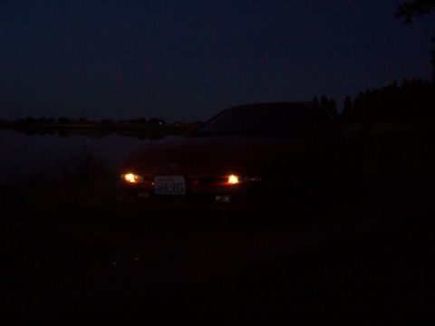 1994 Ford Probe - A car sits by the water at night with its headlights illuminated.