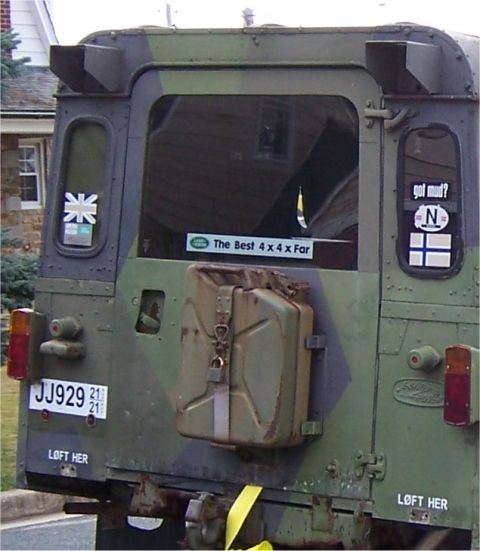 1974 Land Rover Land Rover - This Land Rover Defender features a camouflage paint scheme and a mounted jerry can, along with several stickers on the rear.