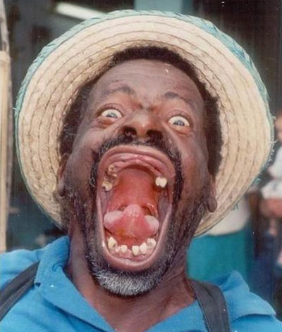 2005 Ford Excursion - Man with an extremely wide open mouth and visible teeth, wearing a hat and blue shirt.