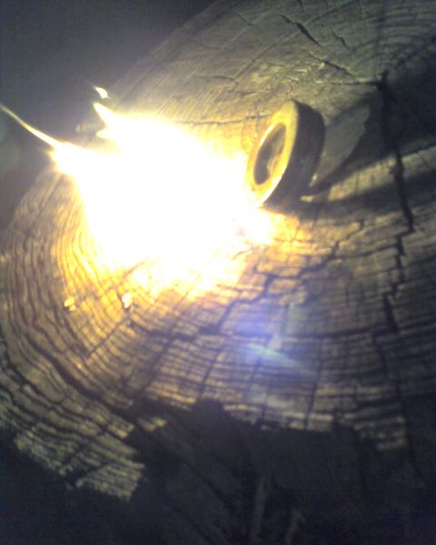 1965 Ford Mustang - A close-up view of a metal ring positioned on a textured wooden surface, illuminated by a bright light source.