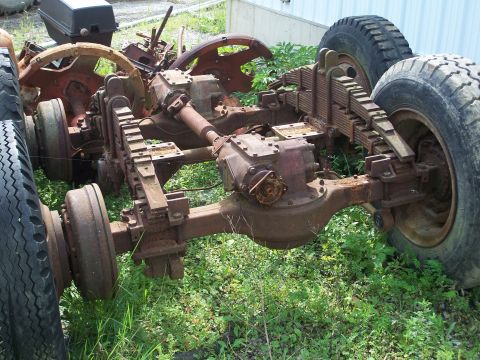 1979 Ford F-150 - This is a close-up view of a heavily rusted truck chassis, showing the drivetrain components and suspension system.