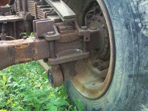 1979 Ford F-150 - Close-up of a heavily rusted truck suspension system and wheel hub, showing wear and tear.
