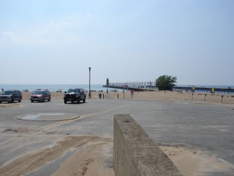 1992 Ford Taurus - A sunny day at the beach with several vehicles parked nearby, overlooking the water and a long pier.