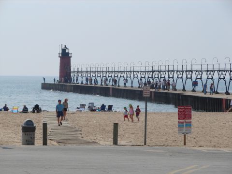 1992 Ford Taurus - A lighthouse stands at the end of a long pier, with beachgoers relaxing on the sand.
