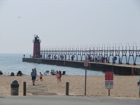 1992 Ford Taurus - A lighthouse stands at the end of a pier on a sunny day with people enjoying the beach.