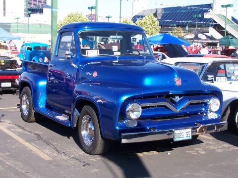 1990 Ford Bronco - A bright blue 1955 Ford F-100 pickup truck is parked at an outdoor event.