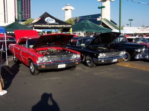 1990 Ford Bronco - Two vintage Ford cars are displayed with their hoods up at an outdoor event.