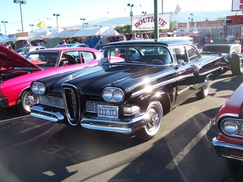 1990 Ford Bronco - A black 1958 Edsel sedan is parked at an outdoor event with other cars and tents in the background.