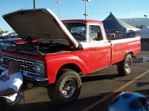 1990 Ford Bronco - A classic red and white pickup truck is displayed with its hood up, revealing the engine bay.