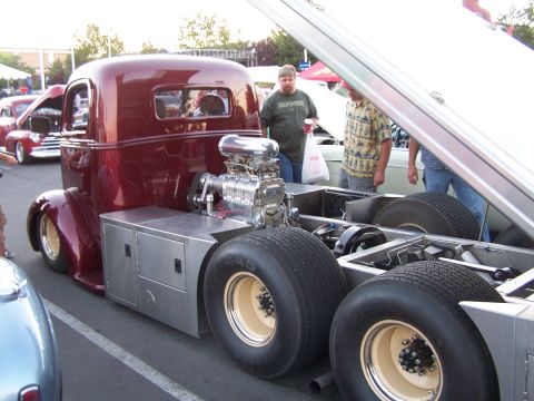 1990 Ford Bronco - A heavily modified truck with a prominent supercharger is displayed at an outdoor event.