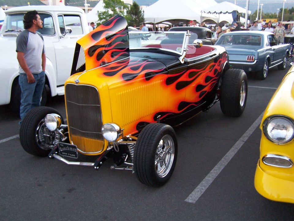 Hot rod with yellow and black flame paint, hood open, parked in a lot