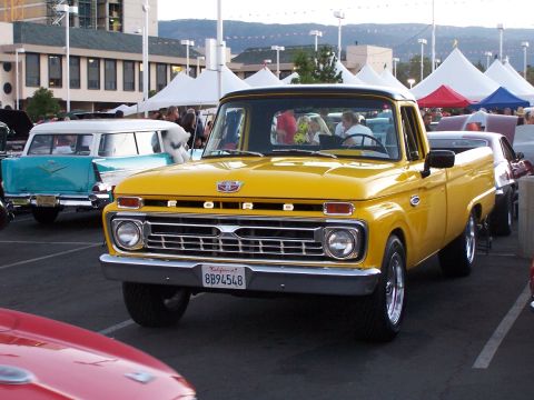 1990 Ford Bronco - This yellow 1965 Ford F-100 pickup truck is parked at an outdoor car show.