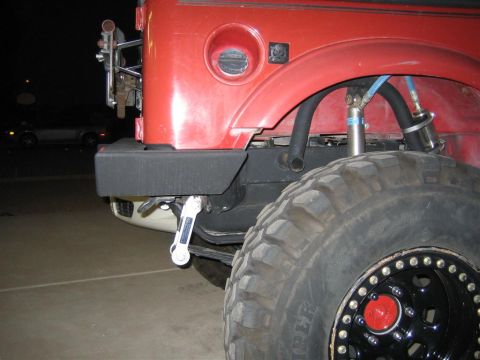 1987 Suzuki Samurai - Close-up of the rear bumper and tire on a red 1987 Suzuki Samurai.
