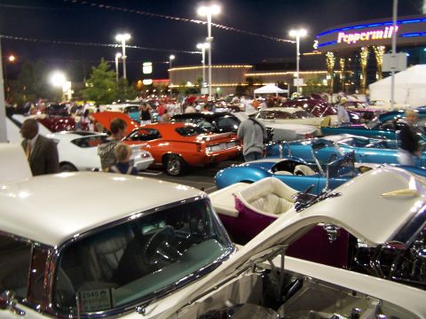 1990 Ford Bronco - A nighttime car show features a variety of classic vehicles under bright lights.