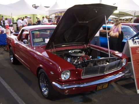 1990 Ford Bronco - Red 1965 Ford Mustang on display at an outdoor event.