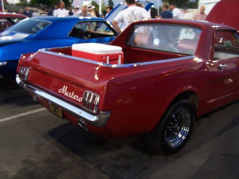 1990 Ford Bronco - A red coupe utility with a cooler in its bed is parked next to a blue car at an outdoor event.