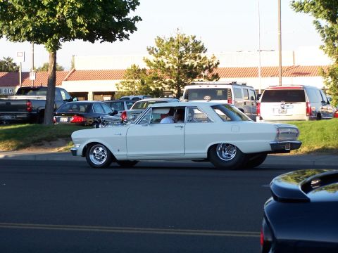 1990 Ford Bronco - Classic white 1964 Chevrolet Nova coupe cruises down the road with custom wheels.
