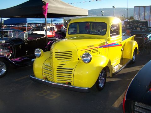 1990 Ford Bronco - A bright yellow vintage Dodge pickup truck is parked at an outdoor car show.