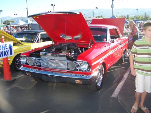 1990 Ford Bronco - A red coupe with its hood open is parked at an outdoor event next to a yellow car.