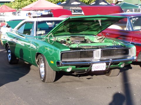 1990 Ford Bronco - A green 1970 Dodge Charger is displayed with its hood open, parked next to a red vehicle.